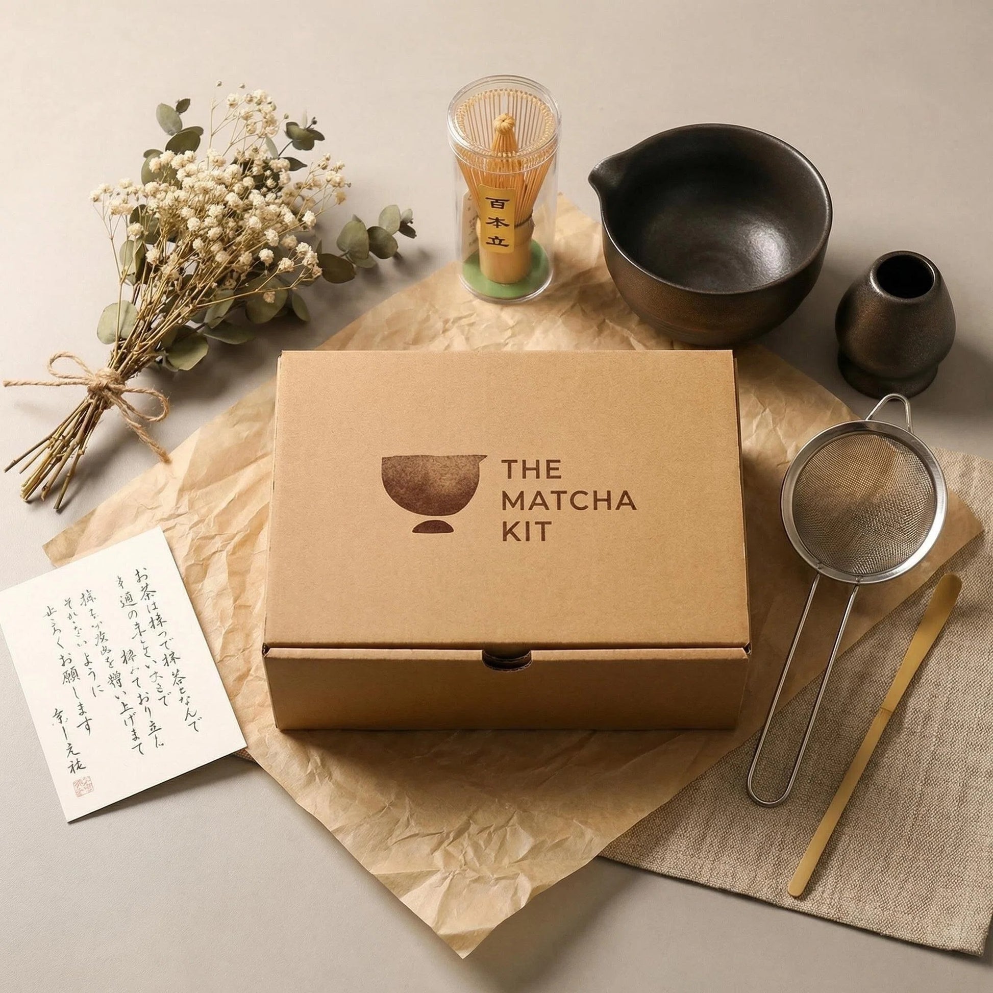 Matcha kit with box, tea bowl, whisk, and other tools on a neutral background